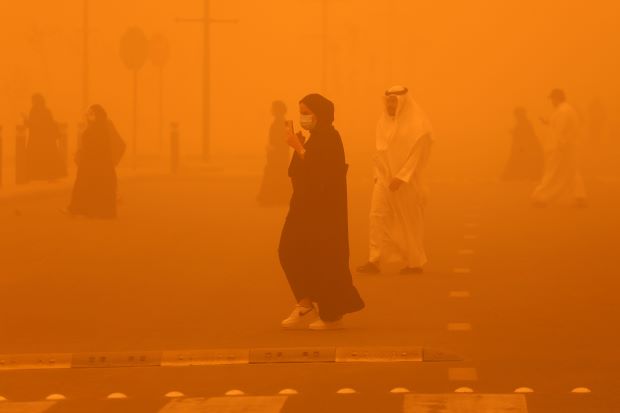 Pedestrians cross a road amidst a severe dust storm in Kuwait City on May 23, 2022.YASSER AL-ZAYYAT/AFP via Getty Images